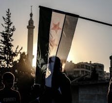 A powerful silhouette of a Syrian flag against a sunset backdrop in Idlib.